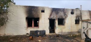 House with heavy smoke damage and windows and door missing.