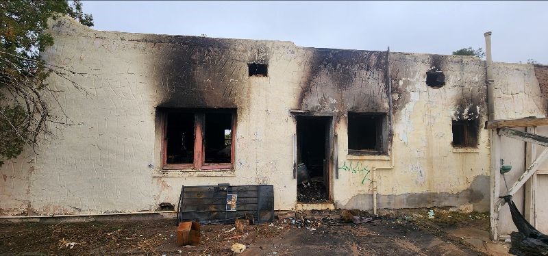 House with heavy smoke damage and windows and door missing.