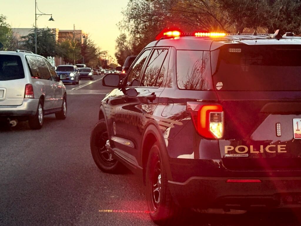 LCPD vehicle parked on the side of the road with their lights on while cars are driving past.
