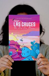 A person holding up a copy of Visit Las Cruces Magazine.