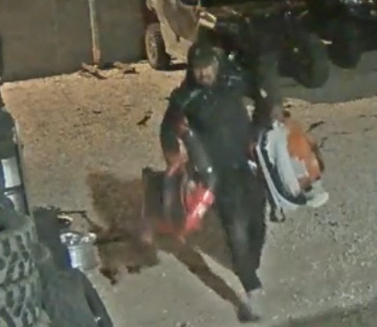 Man, walking while carrying items with both hands.