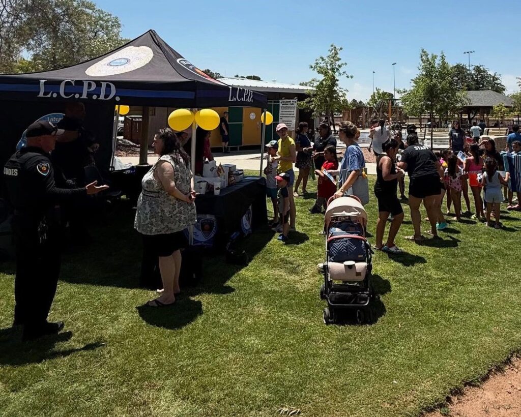 People interacting with police officers in a grassy area outside.