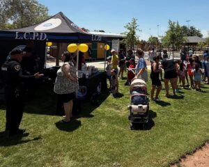 People interacting with police officers in a grassy area outside.