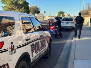NMSU police vehicle parked behind a police motorcycle on the side of a road.
