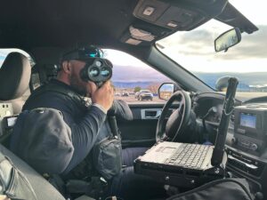 An officer points a radar gun while sitting in his vehicle.