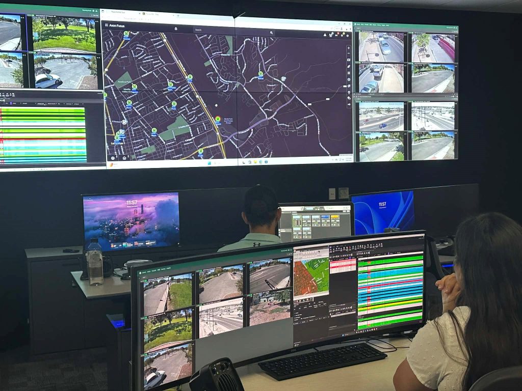 Two people working in front of many screens.