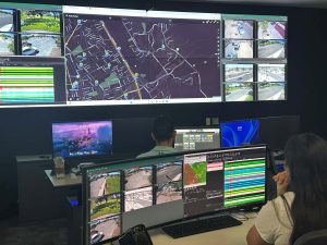 Two people working in front of many screens.
