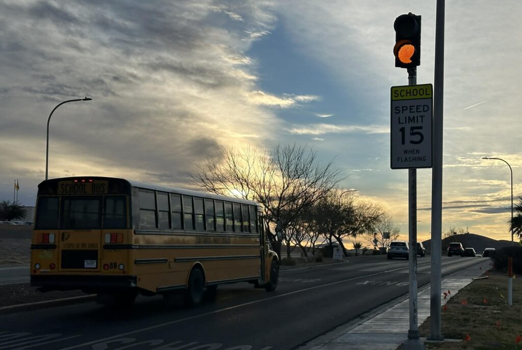 School bus driving past a school crossing sign.