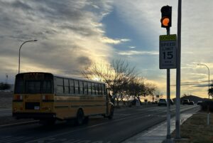 School bus driving past a school crossing sign.