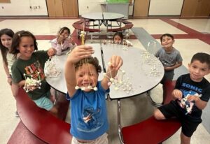 Children sitting at a round table playing with their crafts.