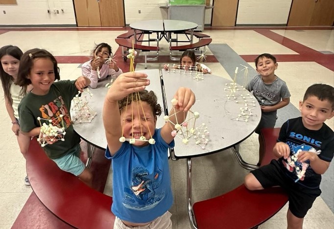 Children sitting at a round table playing with their crafts.