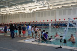 A line of children walking down steps into a swimming pool.