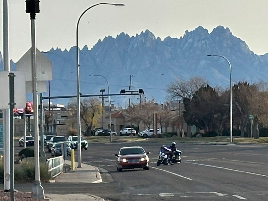 Motorcycle officer stopped in the road and traffic driving on the same road.