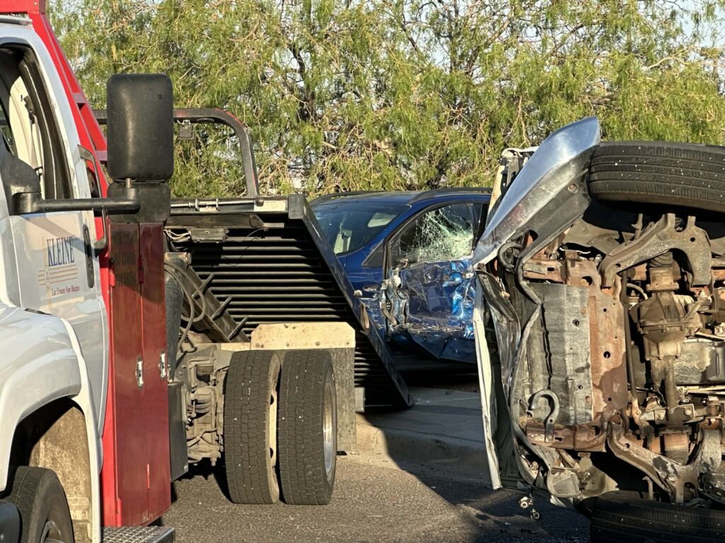 Photo of a tow truck, a wrecker, and two vehicles involved in a crash.