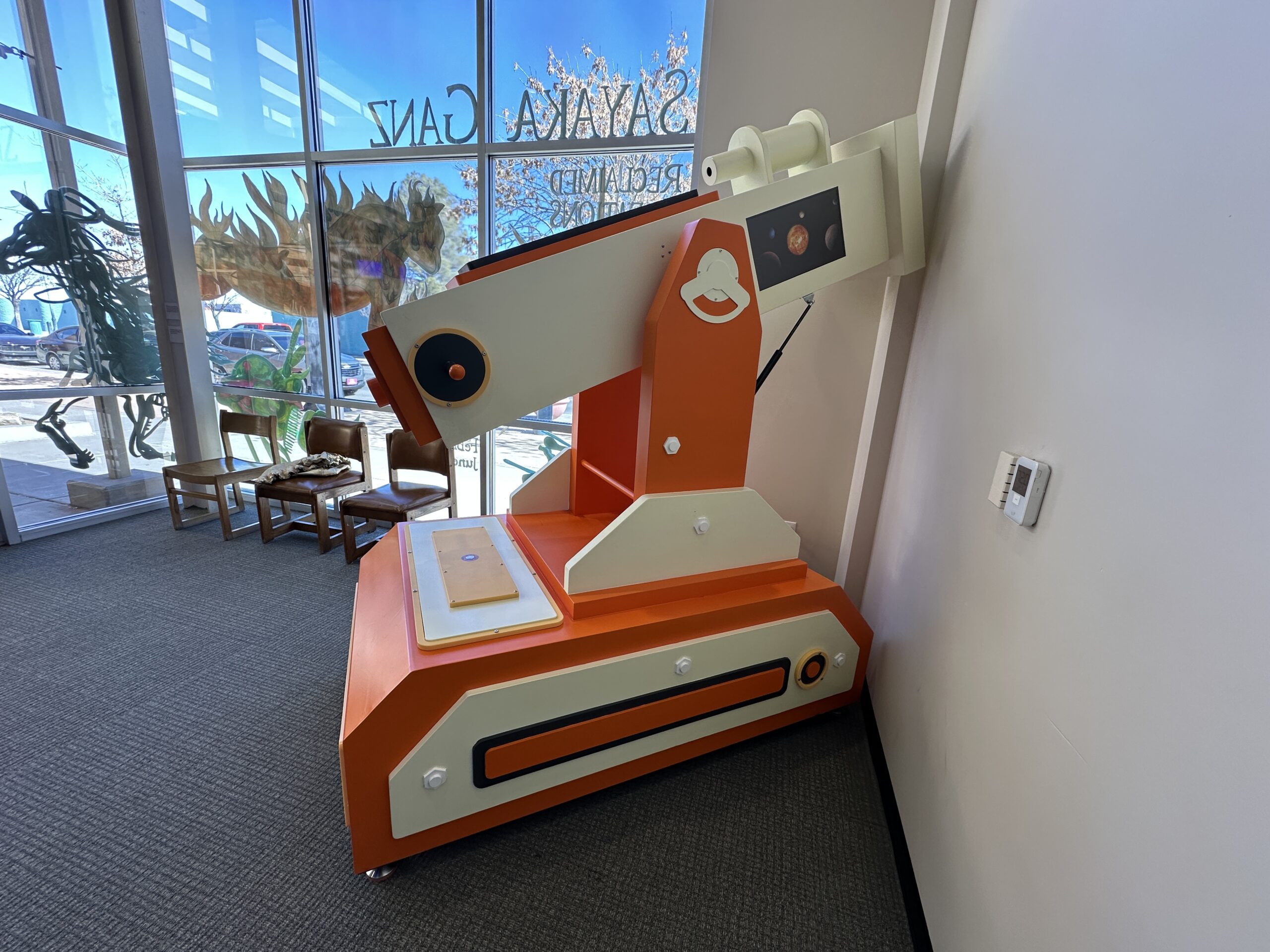 A picture of a large white and orange telescope with a screen displaying a 3d rendering of space.