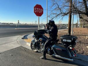 Officer on a motorcycle parked at a stop sign conducting radar.
