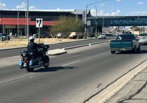 Motorcycle officer riding down a road along with other vehicles.