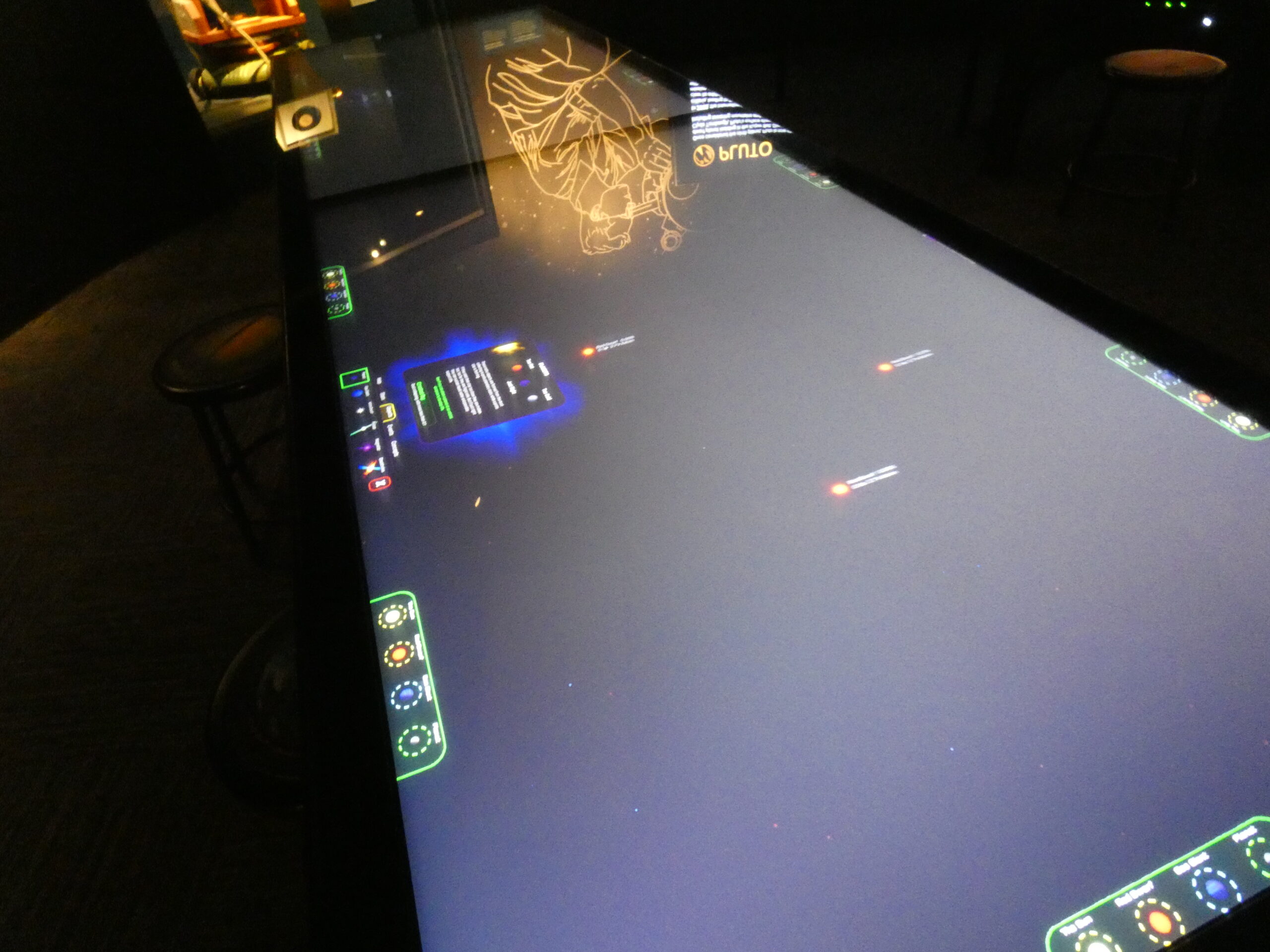 A picture of a table made of two screens showing space with several spots containing suns and planets for players to add onto the space background
