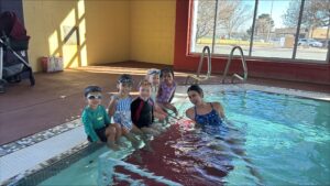 A group of children sitting on the edge of a swimming pool.