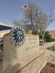 City of Las Cruces Utilities sign with the American flag flying in the background.