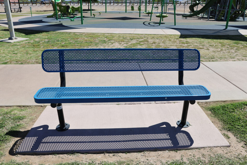 Close up of new blue benches at La Llorona Park with playground in background.