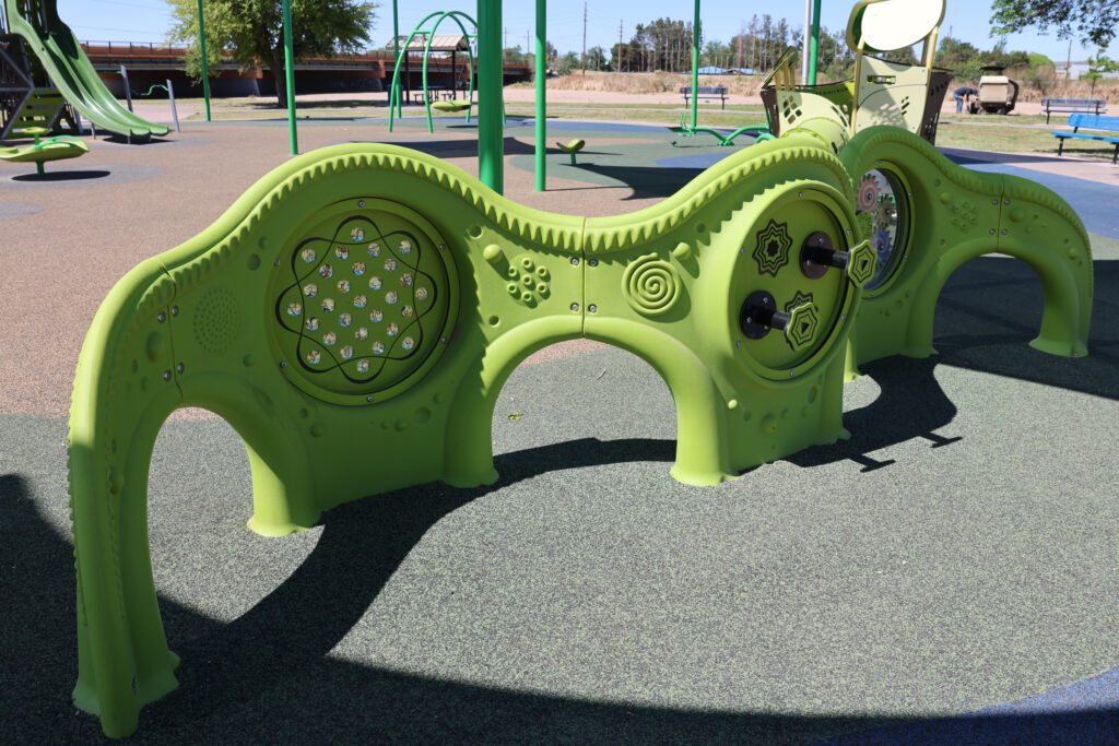Close up of interact inclusive play feature at playground with structures at La Llorona Park over play equipment and soft surface.