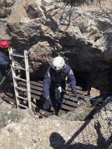 Emergency personnel rappelling into a mine shaft.