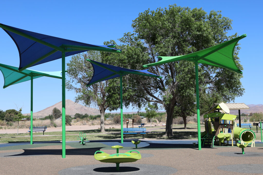 Playground shade structure feature at La Llorona Park over play equipment and soft surface/