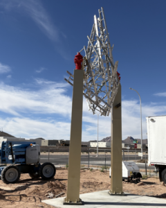 steel columns topped with fire hydrants holding spiky ball made of ladders.