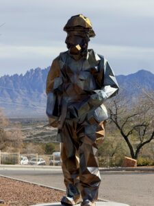 Geometric stylized fire fighter in full gear against Organ Mt. backdrop. 